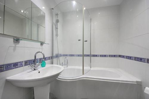 biała łazienka z umywalką i prysznicem w obiekcie Ealing Garden Flat w mieście Ealing