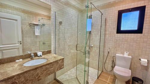 a bathroom with a sink and a glass shower at Loren Suites Corniche in Jeddah