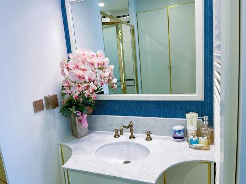 a bathroom with a sink with a mirror and pink flowers at Grand Florida Pattaya By TheBest Management in Na Jomtien