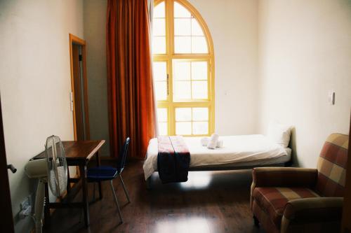um quarto com uma cama, uma mesa e uma janela em Scalabrini Accommodation em Cidade do Cabo