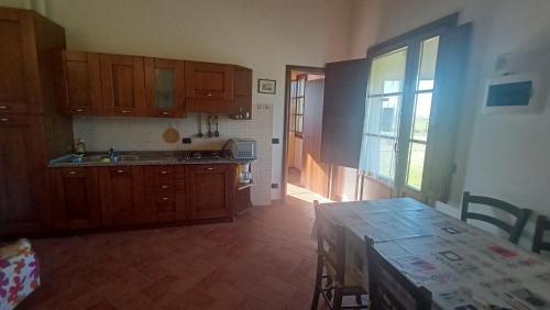 a kitchen with wooden cabinets and a table and a window at il Chiassetto Agriturismo No Kids in Cascina