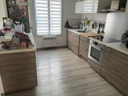uma cozinha com electrodomésticos em aço inoxidável e pisos em madeira em centre Pierrefonds superbe appartement + parking em Pierrefonds