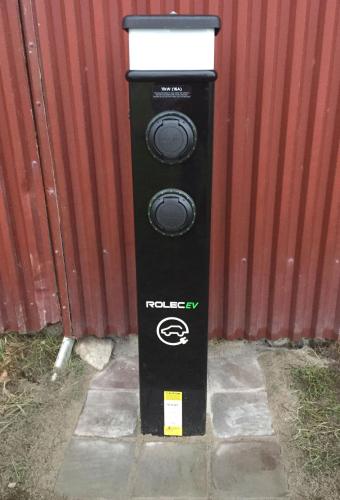 a black parking meter sitting next to a red wall at Lyckås Gårds Gästboende in Höganäs