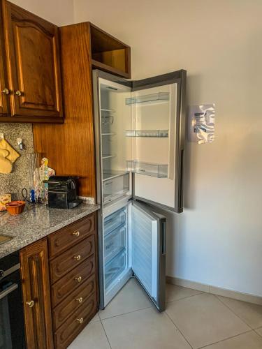 a refrigerator with its door open in a kitchen at Family Espinho Porto Guesthouse in Espinho