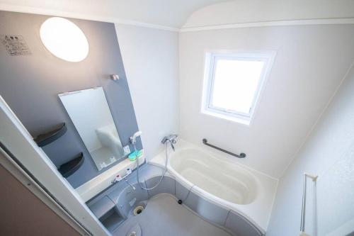 a white bathroom with a tub and a sink at The Sanfurano in Kami-furano