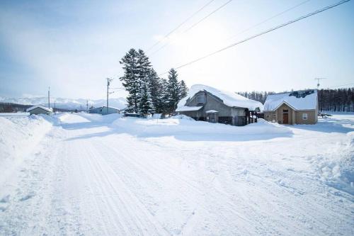 a snow covered road with houses and trees in a village at The Sanfurano in Kami-furano