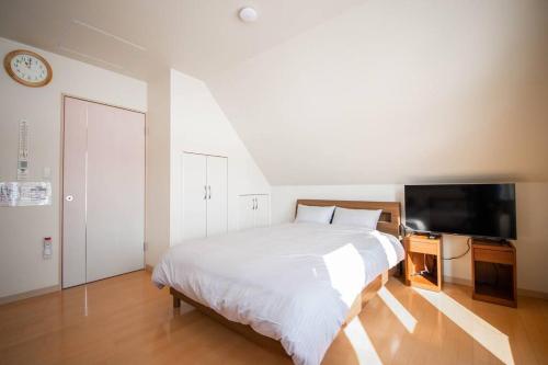 a bedroom with a large bed and a television at The Sanfurano in Kami-furano