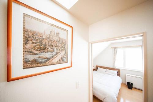 a bedroom with a painting on the wall next to a bed at The Sanfurano in Kami-furano