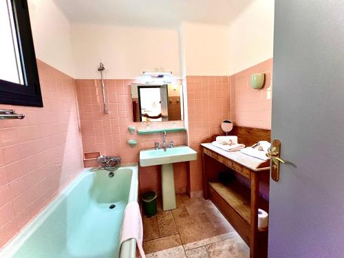 La salle de bains est pourvue d'une baignoire bleue et d'un lavabo. dans l'établissement Annexe Bastide du Paradou, à Moustiers-Sainte-Marie