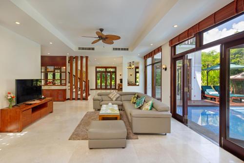ein Wohnzimmer mit einem Sofa und einem TV in der Unterkunft Abogo Resort Villas Luxury Da Nang in Đà Nẵng