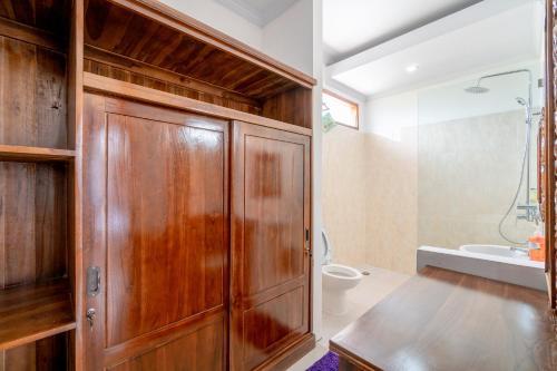 baño con armario de madera y aseo en Lo Sari Bungalow, en Batununggul