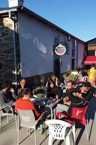 un groupe de personnes assises à des tables à l'extérieur d'un restaurant dans l'établissement Albergue Ponte Ferreira Camino primitivo Lugo Ferreira, à Lugo