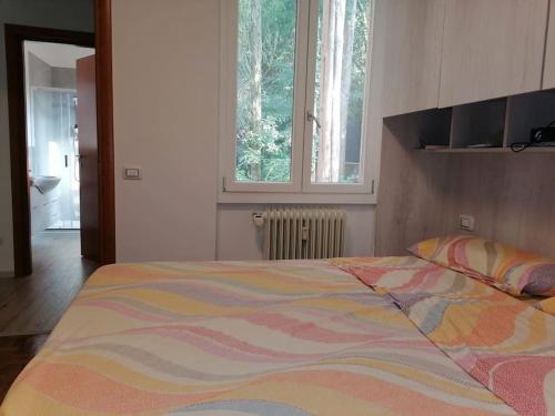 a bedroom with a bed with a colorful comforter and a window at House Of Music in Gardone Riviera