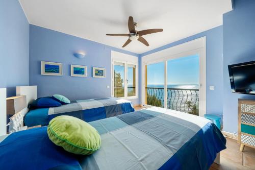 2 camas en una habitación azul con vistas al océano en The beauty of Cala Tamarit, en Tarragona