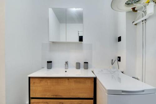 - une cuisine blanche avec un évier et un miroir dans l'établissement Cosy appartement aux Portes de Paris, à Aubervilliers