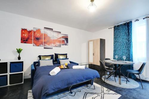 - une chambre avec un lit bleu et une table dans l'établissement Cosy appartement aux Portes de Paris, à Aubervilliers