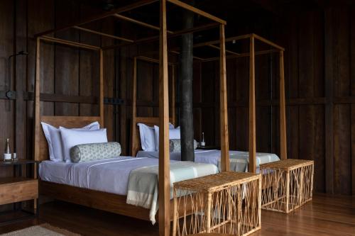 um quarto com 2 camas e paredes de madeira em Trebartha East The Round House em Ahangama