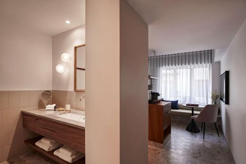 bagno con lavandino e scrivania con sedia di The Social Athens Hotel, a member of Radisson Individuals ad Atene