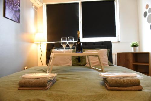 Una cama con dos copas de vino y una mesa. en Siena en Novi Sad