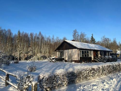 una cabaña de madera en la nieve con una valla en Ferienhaus in Broakulla mit Sauna, en Broakulla