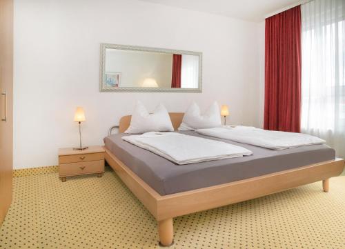 een slaapkamer met een bed met een spiegel en rode gordijnen bij Fairway Hotel in Sankt Leon-Rot