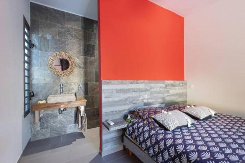 a bedroom with a bed and a sink and red wall at Villa Benjoin St-Pierre Piscine chauffée et mer in Saint-Pierre