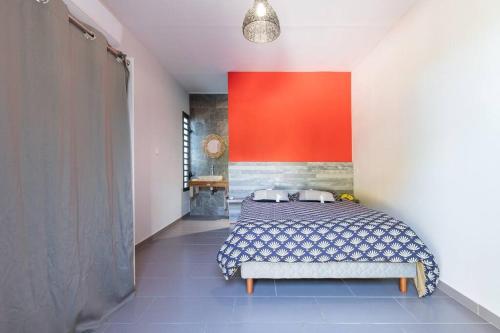 a bedroom with a bed and a red wall at Villa Benjoin St-Pierre Piscine chauffée et mer in Saint-Pierre