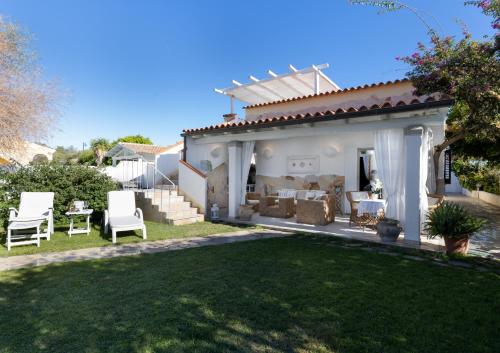 a white house with a yard with white chairs at Casa Perdas - Gate to the Sea by Homey Experience in Olbia