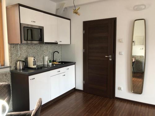 a kitchen with white cabinets and a black counter top at Holiday Apartments Browar Lubicz Krakow Stare Miasto in Kraków