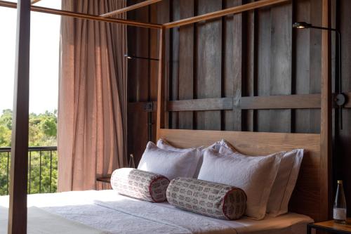 a bedroom with a bed with pillows and a window at Trebartha East The Round House in Ahangama