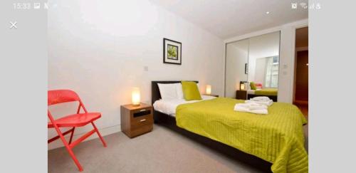 a bedroom with a bed and a red chair at Luxury Holiday Let @ London City in London