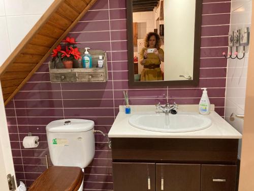 una mujer tomando una foto de un baño con baldosas púrpuras en La Casina Apartamento Turistico centro Plasencia AT-CC-0650, en Plasencia