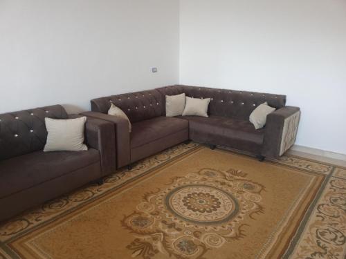 a living room with a brown couch and a rug at Jarash in Jerash