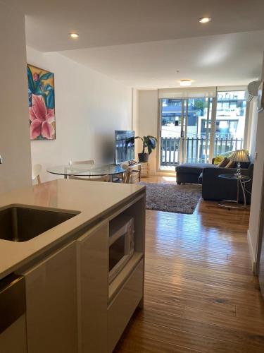 a kitchen with a sink and a living room at Bayside Melbourne Apartment in Melbourne