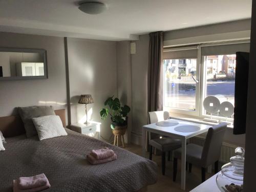 Un dormitorio con una cama y una mesa y una ventana. en Life@Sea, en Zandvoort
