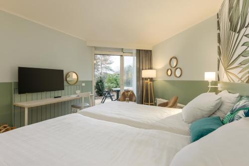 a bedroom with two beds and a flat screen tv at Hotel De Vossemeren by Center Parcs in Lommel