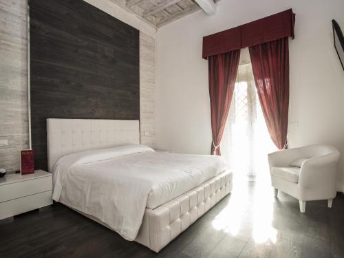 a bedroom with a white bed and a chair at Royal Rooms in Rome