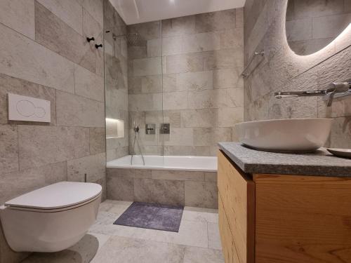 a bathroom with a toilet and a sink and a tub at Riverside 1st Floor South in Saas-Fee
