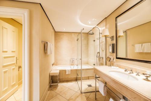 a bathroom with a tub and a sink and a mirror at Rheinhotel Schulz in Unkel