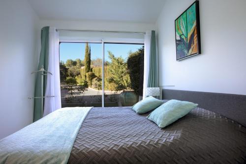 a bedroom with a large bed with a large window at Appartement - Clos Saint Jean in Roquebrune-sur-Argens