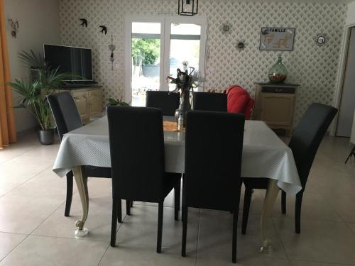 une salle à manger avec une table blanche et des chaises noires dans l'établissement Au Vieux Bourg, à Guécélard