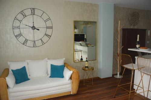 sala de estar con sofá blanco y reloj en la pared en moderne Ferienwohnung, en Merano