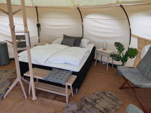 a bedroom with a bed and a chair in a tent at Terrassen Camping & Cottages in Silkeborg