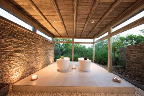 a patio with two white chairs and a brick wall at Kapama Karula in Kapama Private Game Reserve