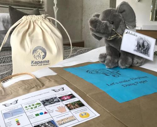 a stuffed elephant sitting on a bed next to a bag at Kapama Southern Camp in Kapama Private Game Reserve