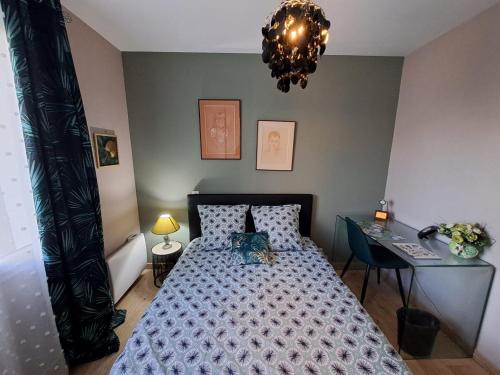 a bedroom with a bed and a desk and a chandelier at - Maison Capucine- Proche centre d'affaire Chauray, Jardin, parking, WIFI et Netflix, idéal voyage d'affaire, familles, ou simple escapade in Chauray