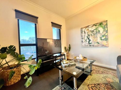 un soggiorno con TV e tavolo in vetro di Stylish Self-contained Apartment a South Hedland
