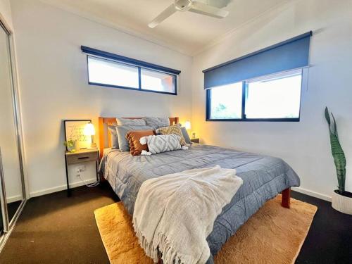 a bedroom with a bed and two windows at Stylish Self-contained Apartment in South Hedland