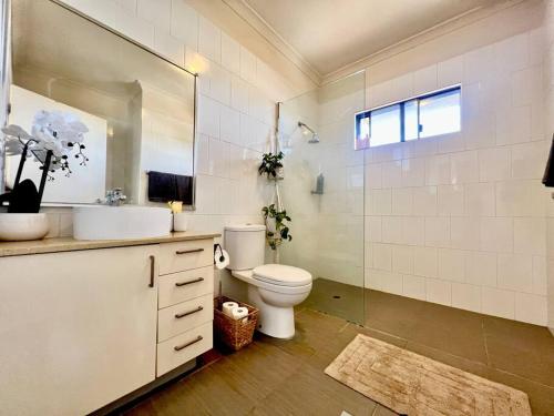 a bathroom with a toilet and a sink and a mirror at Stylish Self-contained Apartment in South Hedland
