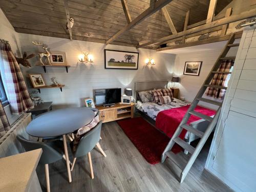 1 dormitorio con cama, escritorio y escalera en Luxury Woodland Lodge, en Newport Pagnell